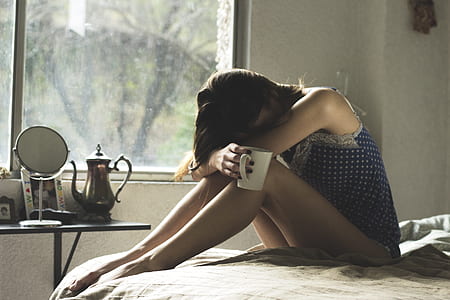 woman sitting on bed holding white cup thumbnail