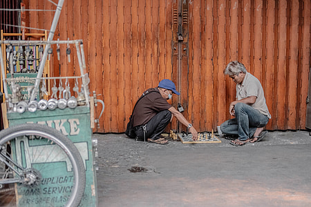 photo of two person playing chess beside roller shutter thumbnail