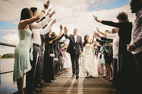 groom and bride walking on isle while giving high-five under white cloudy skies at daytime thumbnail