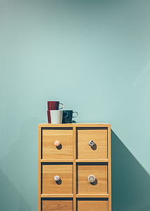 red, green, and white ceramic mugs on top of brown wooden dresser thumbnail