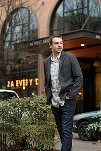 man wearing gray blazer walking near green car thumbnail