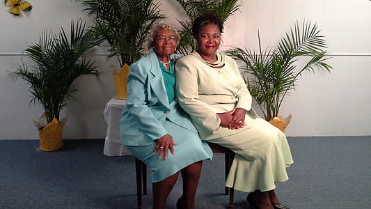 two women in blue and white dresses sitting on brown chair thumbnail