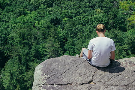 woman sitting on rocky hill viewing forest thumbnail