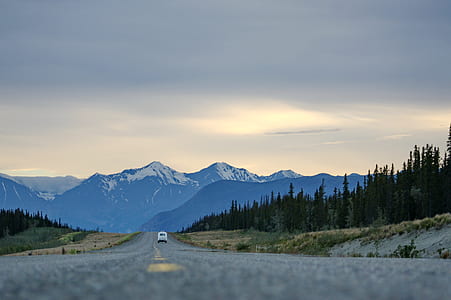 white driving on asphalt road towards mountains thumbnail