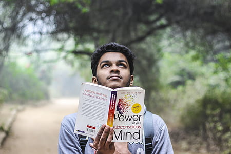 Man in Grey Shirt Holding Opened Book Looking Upward thumbnail