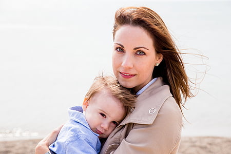 woman in brown top carrying toddler in blue top thumbnail