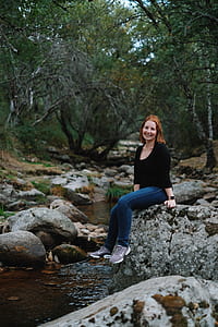 selective focus photo of woman sitting on rock at river thumbnail