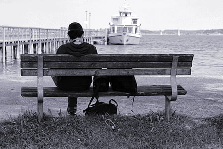 grayscale photo of person sitting on bench thumbnail