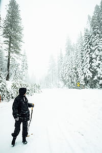 man wearing snow coat standing on snow-covered road thumbnail