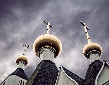 low angle photography of three gray towers with crosses under cloudy sky thumbnail