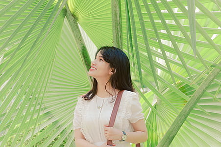 Smiling Woman Standing Near Green Leaf Plants thumbnail
