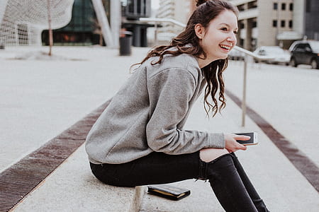 woman sitting on sidewalk holding smartphone thumbnail