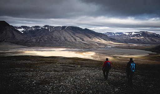 two men walking on field facing mountain range thumbnail