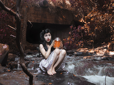 sitting woman holding glass jar on black stone with crushing water thumbnail