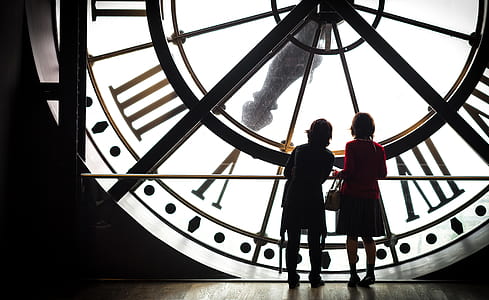silhouette view of two women standing in front of big clock thumbnail