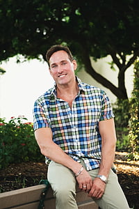 man sitting on wooden bench smiling thumbnail