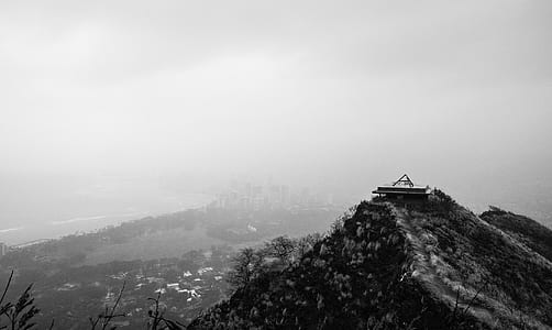 grayscale photo of house on top of mountain thumbnail