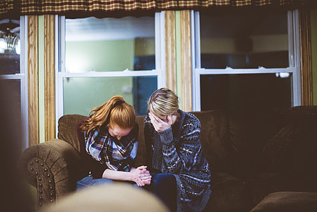 two women crying together while sitting sofa thumbnail
