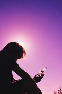 silhouette photography of person holding clear glass bottle thumbnail