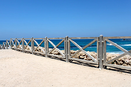 gray fence beside rocks on shore thumbnail