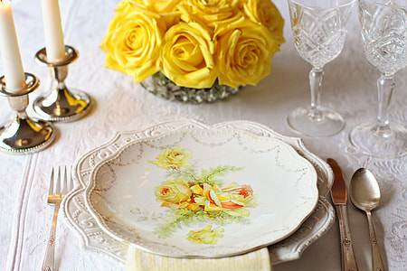 white and yellow floral ceramic plate near butter knife and spoon table setting thumbnail