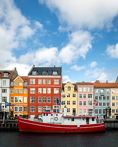 red and white motored boat on water body under blue sky and white clouds thumbnail
