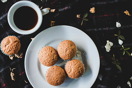 four muffins on white ceramic plate beside mug with black liquid thumbnail