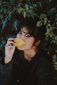woman in black top holding brown leaf thumbnail