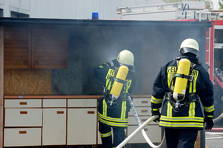 firefighter holding hose near house thumbnail