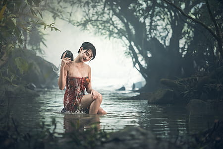 woman wearing maroon and red strapless dress taking a bath on river thumbnail