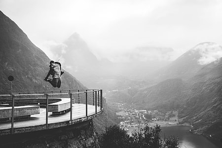 grayscale photo of man jumping near fence thumbnail