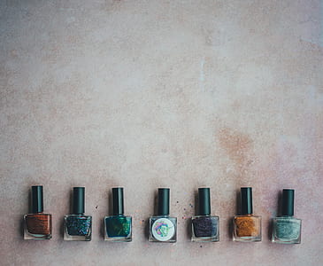 seven assorted-color nail polish bottles on gray surface thumbnail