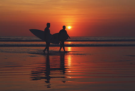 silhouette of two men holding surfboards thumbnail