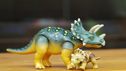 green triceratops and brown baby triceratops figures on brown surface thumbnail