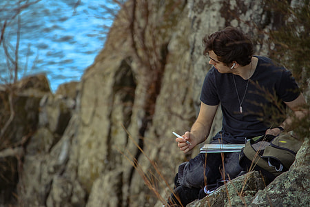 man writing on top of the mountain near sea at daytime thumbnail