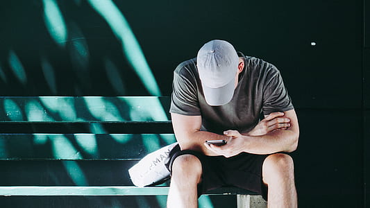 sitting man on bench while looking on his phone thumbnail