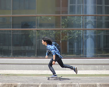 man riding skateboard in front of clear glass building thumbnail