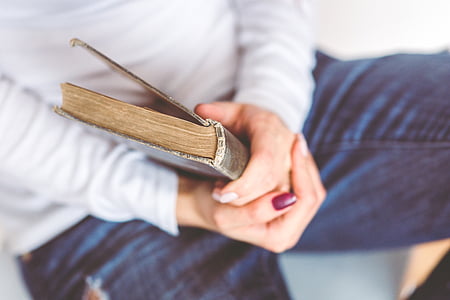 person sitting on white surface while holding a book thumbnail
