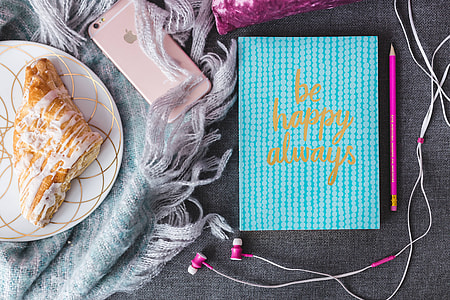 Blue notebook with a pink iPhone, headphones and a sweet bun thumbnail