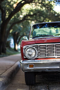red vehicle on street near tree during daytime thumbnail