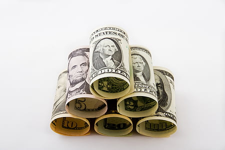pyramid stacked rolled US dollars on white surface thumbnail