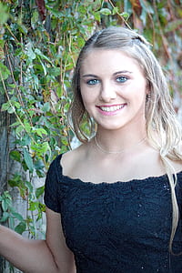 woman smiling while leaning her hand on gray wall thumbnail