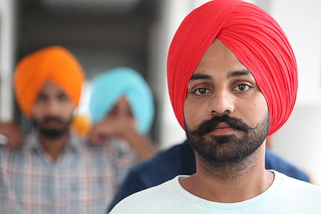 selective focus photograph of man wearing red turban and white crew-neck shirt thumbnail