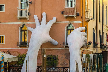 two gray stoned hands statue holding on brown high-rise building thumbnail