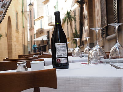 black wine bottle on white table beside brown wooden chair thumbnail