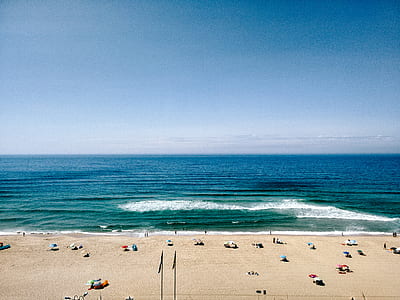 people walking on shore by the sea at daytime thumbnail