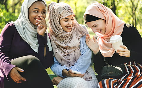Photo of Women Laughing and Dressed in Hijabs Sitting Next to Each Other. thumbnail