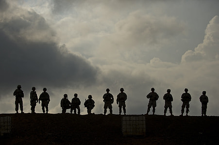 silhouette photography of soldiers standing under clouds thumbnail