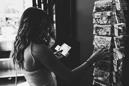 gray scale photo of woman holding postcards thumbnail