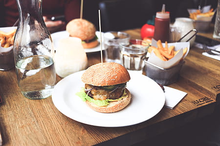 selective focus photography of burger on white plate on top of brown table thumbnail